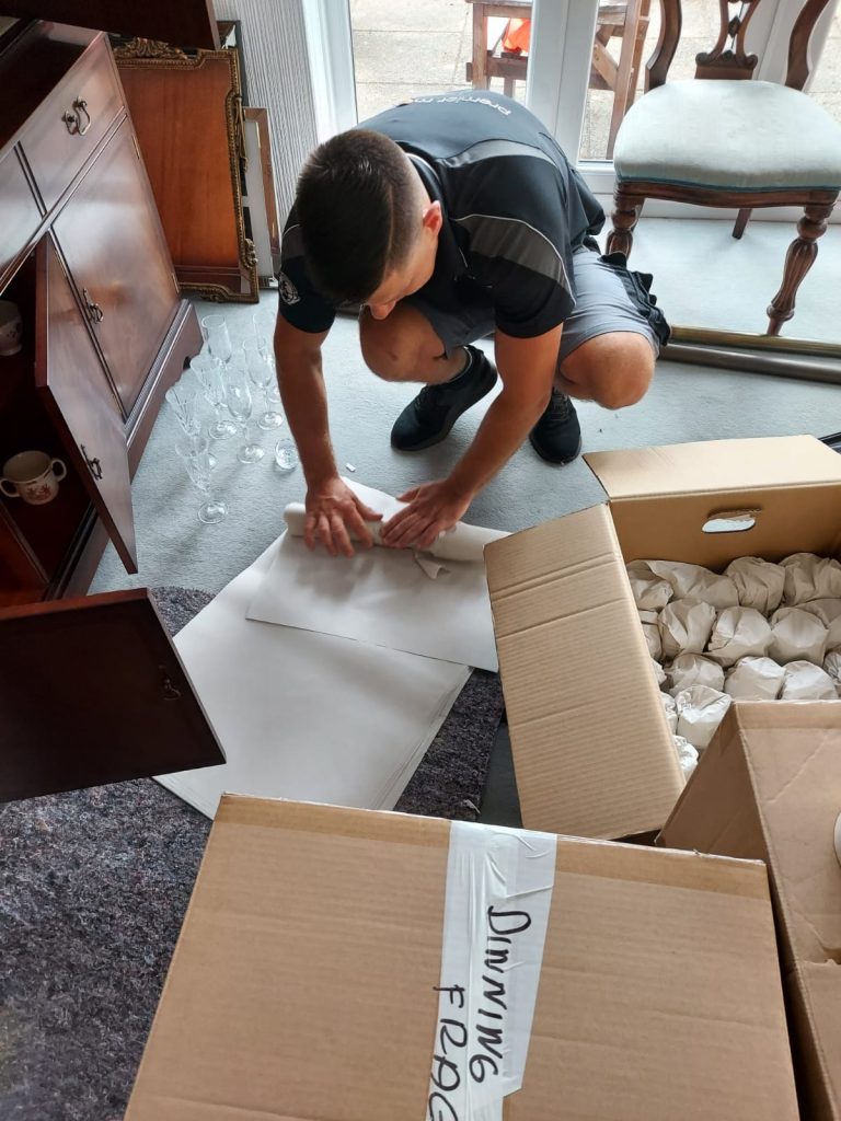 Picture of a premier movers specialist carefully loading up a box with wrapped items